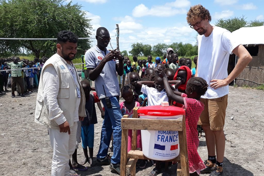 Aburoc's children teach Baptiste how to wash his hands properly.